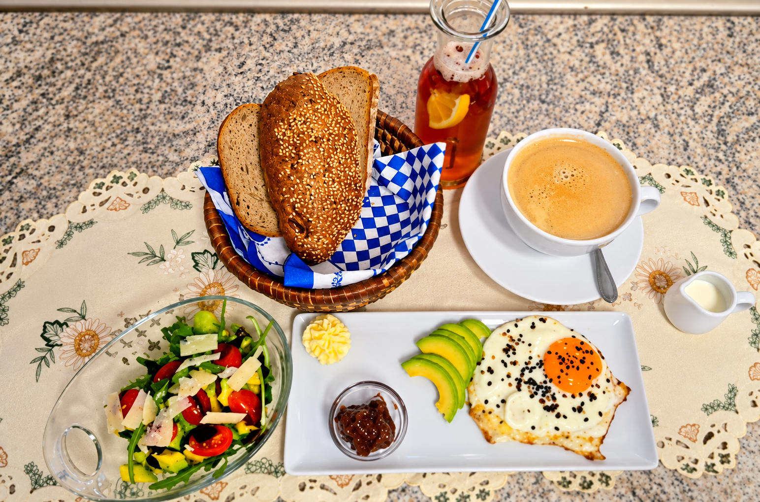 Reichhaltiges Frühstück mit Brötchenkorb, Spiegelei mit Avocado, Salat und Café Crema